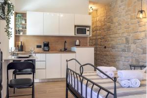 a kitchen with white cabinets and a brick wall at TEONA Luxury Studio Apartment with jacuzzi and garden view in Sali