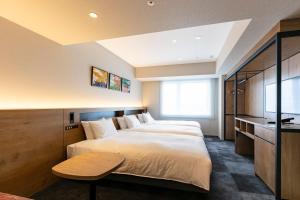 a bedroom with two beds and a table in it at Hotel Forza Osaka Namba in Osaka