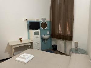 a room with a bed and a television and a sink at Albergo Novecento in Genoa