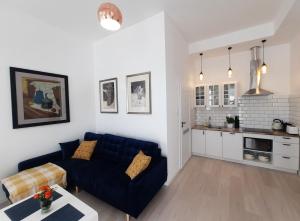 salon z niebieską kanapą i kuchnią w obiekcie Apartamenty Jantar w mieście Giżycko