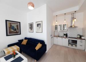 salon z niebieską kanapą i kuchnią w obiekcie Apartamenty Jantar w mieście Giżycko