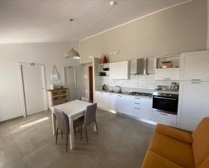 a kitchen with white cabinets and a table and chairs at Villetta al mare Scanzano Jonico in Scanzano