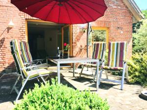 a patio with a table and chairs and a red umbrella at Hinners-Hoff Apartments in Bendingbostel
