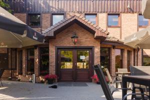 a building with a wooden door with a cat sitting in front at Hotel Restauracja Biały Las Wierzbna in Żarów