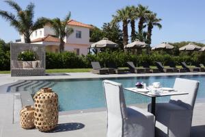 a swimming pool with a table and chairs next to a house at Lagouvardos Village Hotel in Marathopoli