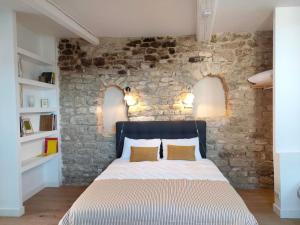 a bed in a room with a stone wall at La Maison près de la Fontaine in Saignon