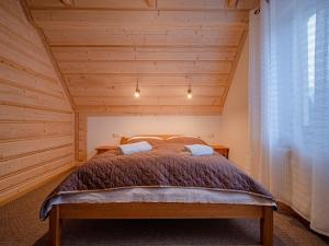 een slaapkamer met een bed in een kamer met houten plafonds bij Tatrzańska Kryjówka Premium Chalets Zakopane in Poronin