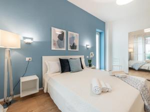 カリアリにあるAcquaChiara Suiteのベッドルーム1室(青い壁の大きな白いベッド1台付)