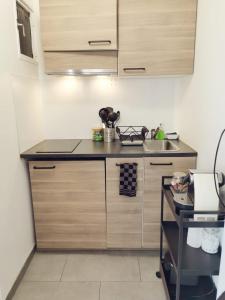 una pequeña cocina con armarios de madera y fregadero en Suite Athéna - Melun gare RER - Studio avec Balcon et parking en Melun