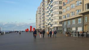 a group of people walking down a street next to buildings at frontaal gelijkvloers seaview 80m² 2 slp in Ostend