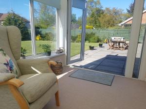 a screened in porch with a chair and a table at The Burrow, a Spacious Bungalow in Heart of NI in Templepatrick