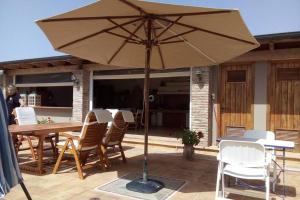 an umbrella on a patio with chairs and a table at The Orange Grove Garden Room in Mytikas +9 photos