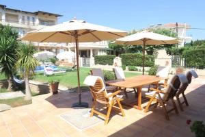 a wooden table and chairs with an umbrella at The Orange Grove Garden Room in Mytikas