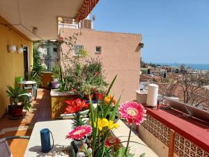 Un balcón con una mesa con flores. en Pedregalejo Room en Málaga