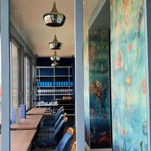 a dining room with blue chairs and paintings on the walls at Hôtel Restaurant L'Atelier des Cousins in Châtelaillon-Plage