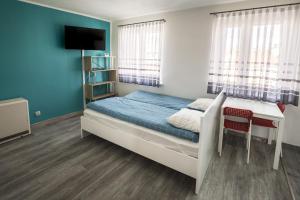 een slaapkamer met een bed, een bureau en een televisie bij High Floor Vision Apartment in Opole