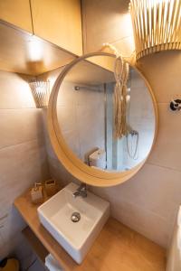 a bathroom with a sink and a round mirror at En Lefko Boutique Apartments in Nikiana