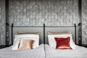 a bedroom with a bed with white sheets and red pillows at Original Sokos Hotel Arina Oulu in Oulu