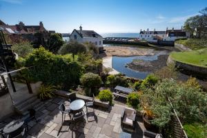 un patio con mesa y sillas junto a un río en The Bank, en Anstruther