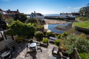 a patio with a table and chairs next to a river at The Bank in Anstruther
