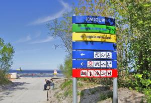 a sign at the beach with people sitting next to it at Skolas street seaside space! in Jūrmala