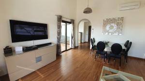 a living room with a dining table and a flat screen tv at Villa BELLA on Golf in La Estancia, Caleta Fuste-Fuerteventura in Caleta De Fuste