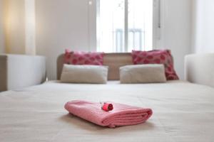 een roze handdoek bovenop een bed bij PRECIOSO Y PEQUEÑO LOFT CENTRO DE CONIL in Conil de la Frontera