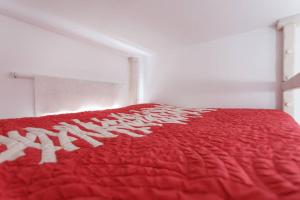 a bed with a red comforter on top of it at PRECIOSO Y PEQUEÑO LOFT CENTRO DE CONIL in Conil de la Frontera