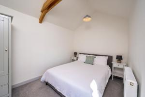 a white bedroom with a bed and a night stand at Cart Shed Cottage in Truro