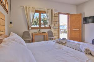 1 dormitorio con 1 cama blanca grande y toallas. en The Wave House, en Mókhlos