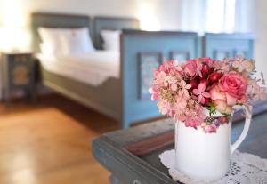 a white vase with flowers on a table in a bedroom at Gentner - Hotel garni in Gnotzheim