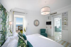 um quarto com uma cama branca e uma cadeira azul em Luxury Villa Malika - Great View on Capri&Positano em Praiano