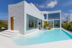 a villa with a swimming pool in front of a house at AQUABLANCA Suite Love Deluxe en Punta Mujeres in Punta de Mujeres