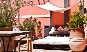 um pátio com duas camas e uma mesa e vasos de plantas em Riad Safa em Marraquexe