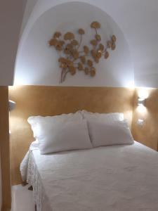 um quarto com uma cama branca com uma flor na parede em Casetta Melograno em Fasano