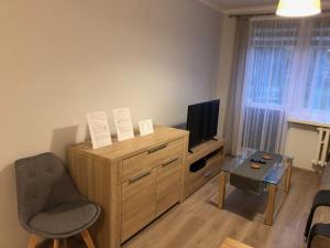 salon z telewizorem i drewnianą komodą w obiekcie Apartament na Wierzbowej parter w Kędzierzynie-Koźlu