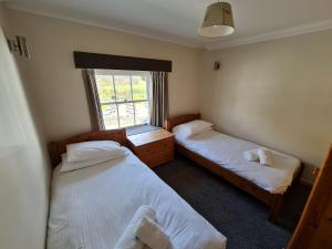 two beds in a room with a window at Stable Cottage in Penrith