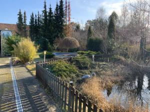 a park with a fence and a pond with birds in it at Zur Alten Tischlerei in Karlshagen