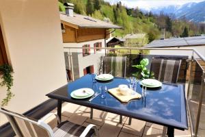 una mesa azul y sillas en el balcón en Chalet Schmittenbach - Pinzgau Holidays, en Zell am See