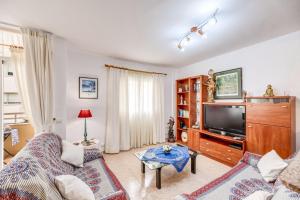 a living room with a couch and a tv at Espectacular Apartamento in Port de Pollensa