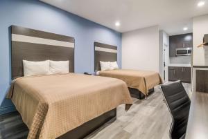 una habitación de hotel con 2 camas y una silla en Studio 6 Deer Park, Tx en Deer Park