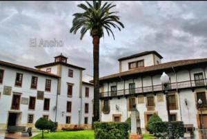 a palm tree in front of a white building at Apartamento Conlledo in Villaviciosa