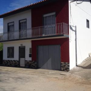 a red and white house with a balcony at Moradia Bispo in Aljubarrota