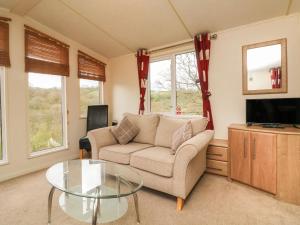 a living room with a couch and a glass table at Exe Valley Lodge in Tiverton