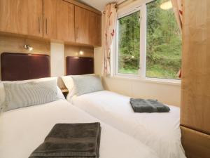 twee bedden in een kleine kamer met een raam bij Exe Valley Lodge in Tiverton