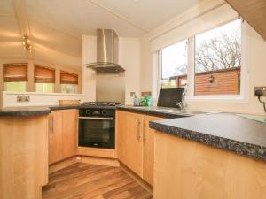 een keuken met houten kasten en een fornuis met oven bij Exe Valley Lodge in Tiverton