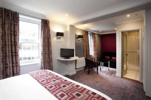 ノッティンガムにあるSt James Hotel; BW Premier Collectionのベッド、デスク、テレビが備わるホテルルームです。