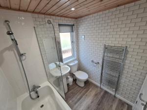 a bathroom with a toilet and a sink and a tub at Park Lodge in Penrith