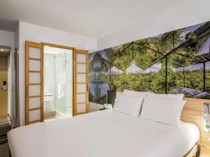 ein Schlafzimmer mit einem großen weißen Bett mit einem Gemälde an der Wand in der Unterkunft Novotel Den Haag City Centre, fully renovated in Den Haag