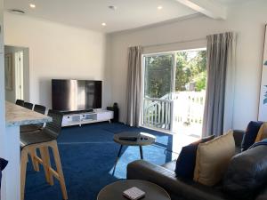 a living room with a couch and a television at Coromandel Town Harbourside Cottage Luxury Accommodation in Coromandel Town